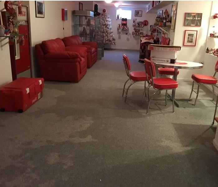 Basement of a home showing areas of wet carpet.