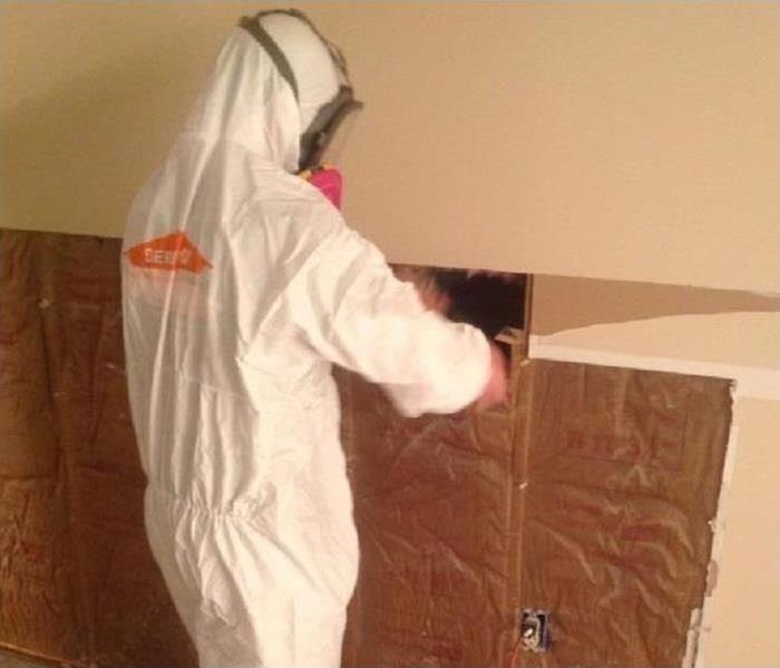 Technician wearing protective gear, while installing new insulation on wall after water and fire damage